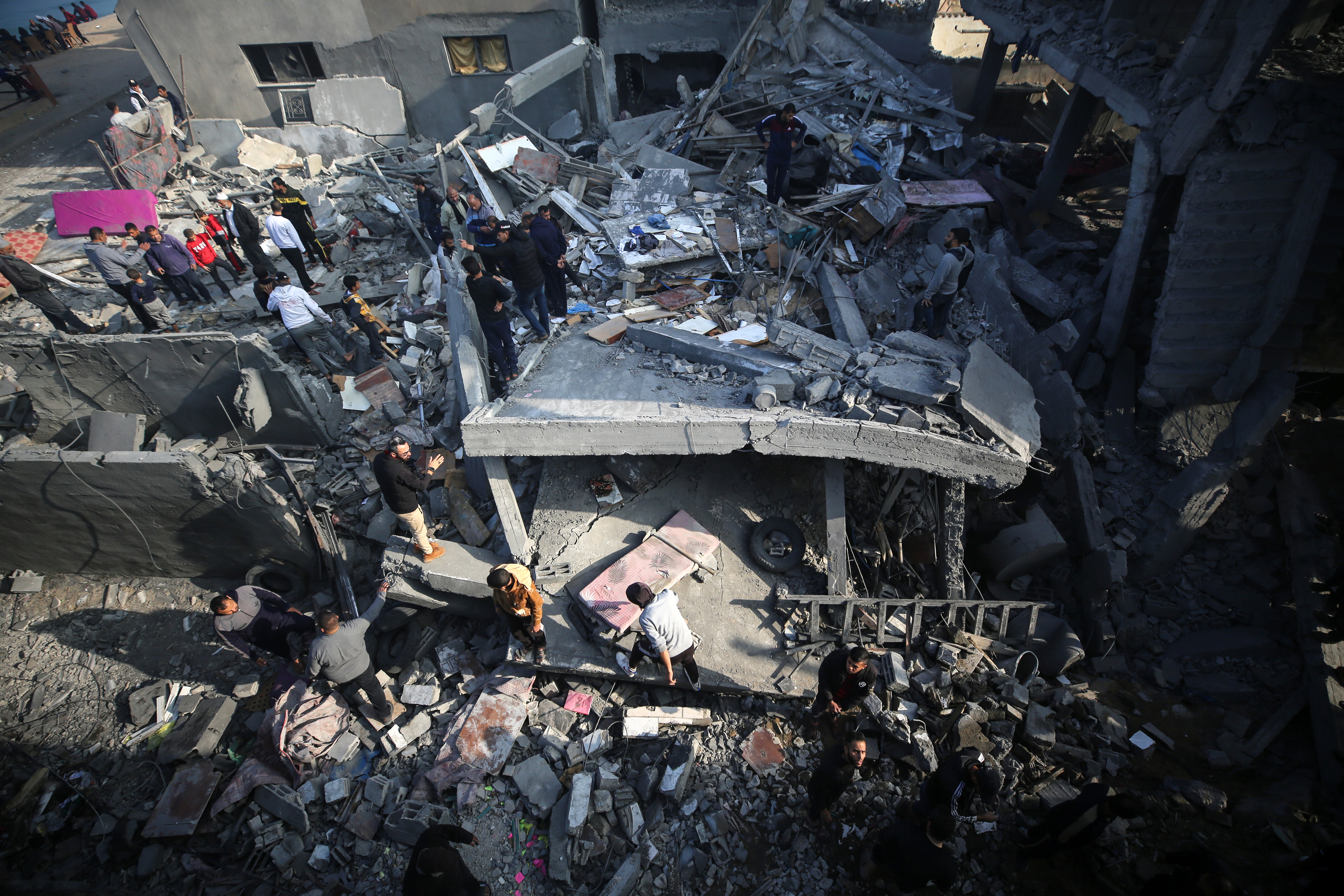 Aerial view of people amidst the rubble of a collapsed building, indicating a disaster site