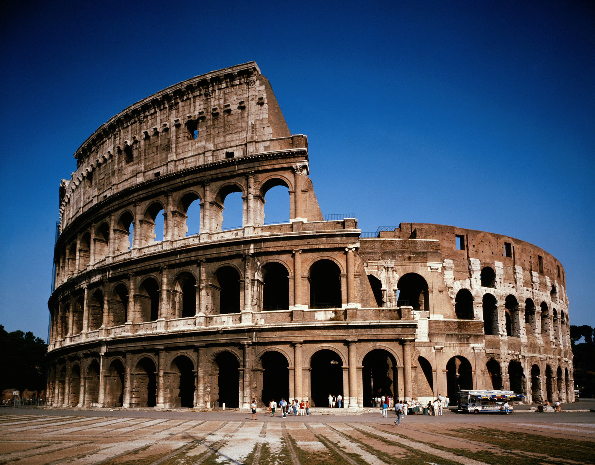 Exterior view of the Colosseum in Rome, showing the ancient structure&#x27;s arches and partial ruins