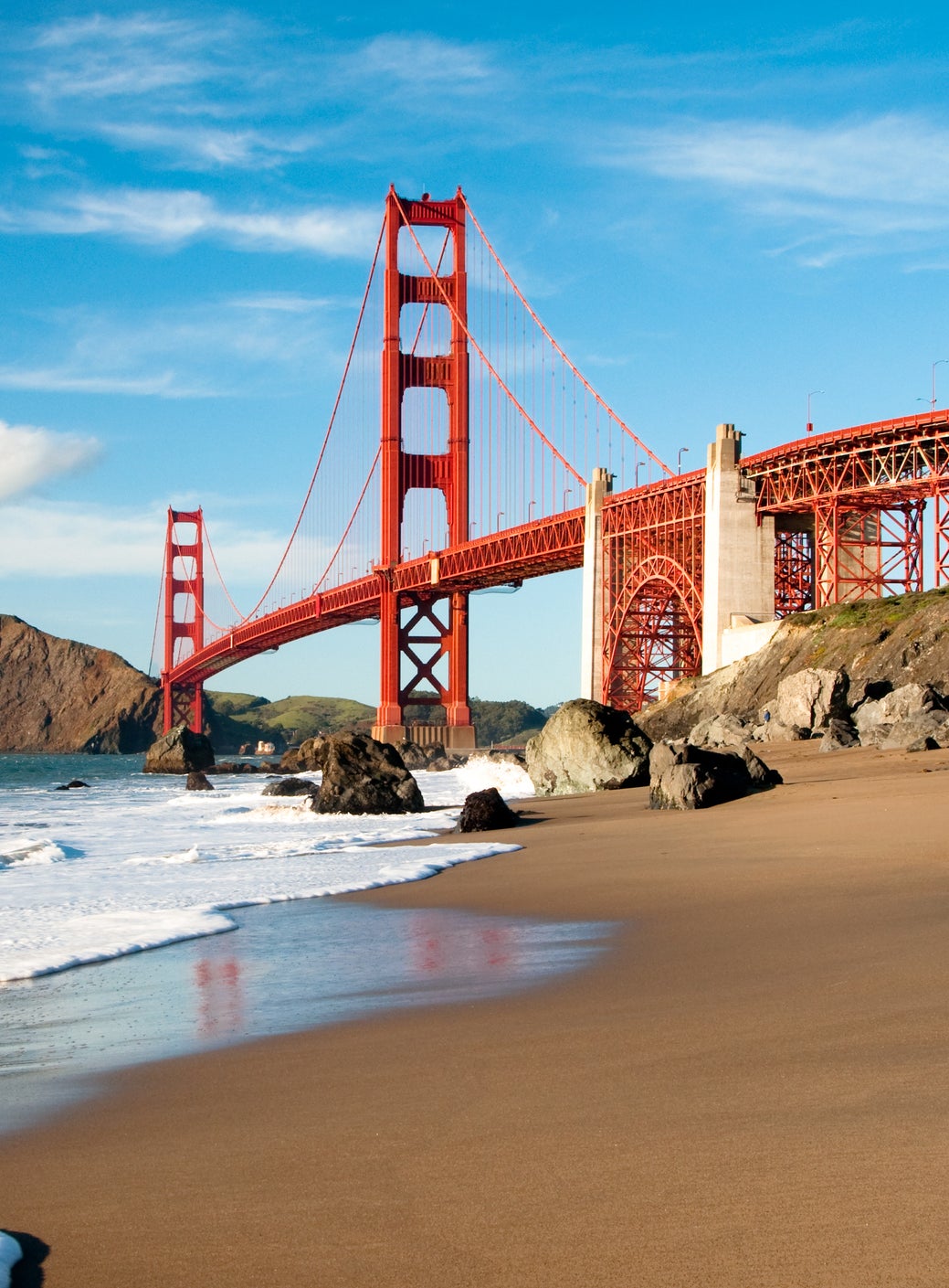 Golden Gate Bridge viewed from a sandy beach with waves in the foreground