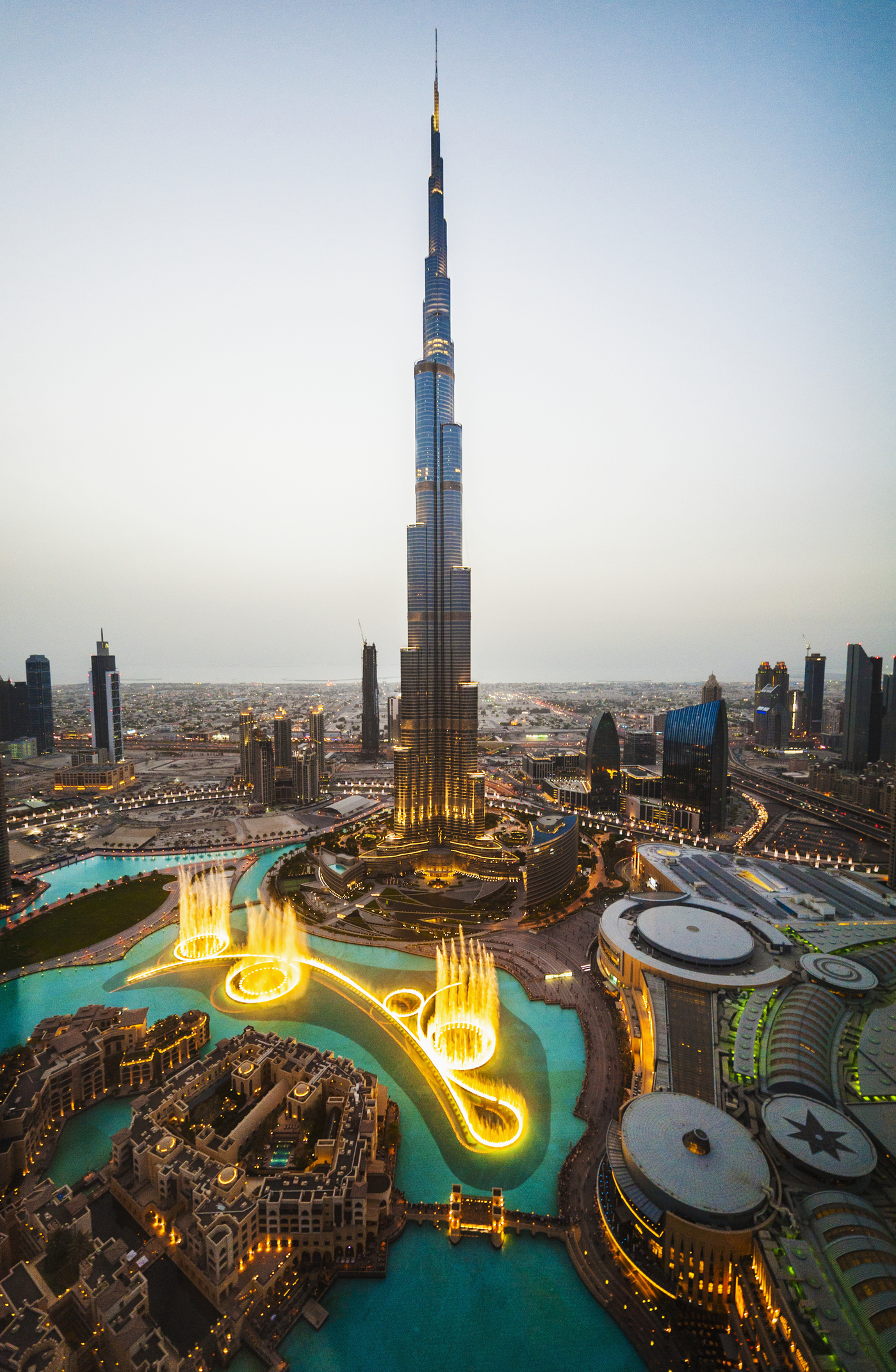 Aerial view of the Burj Khalifa and surrounding illuminated water features at dusk