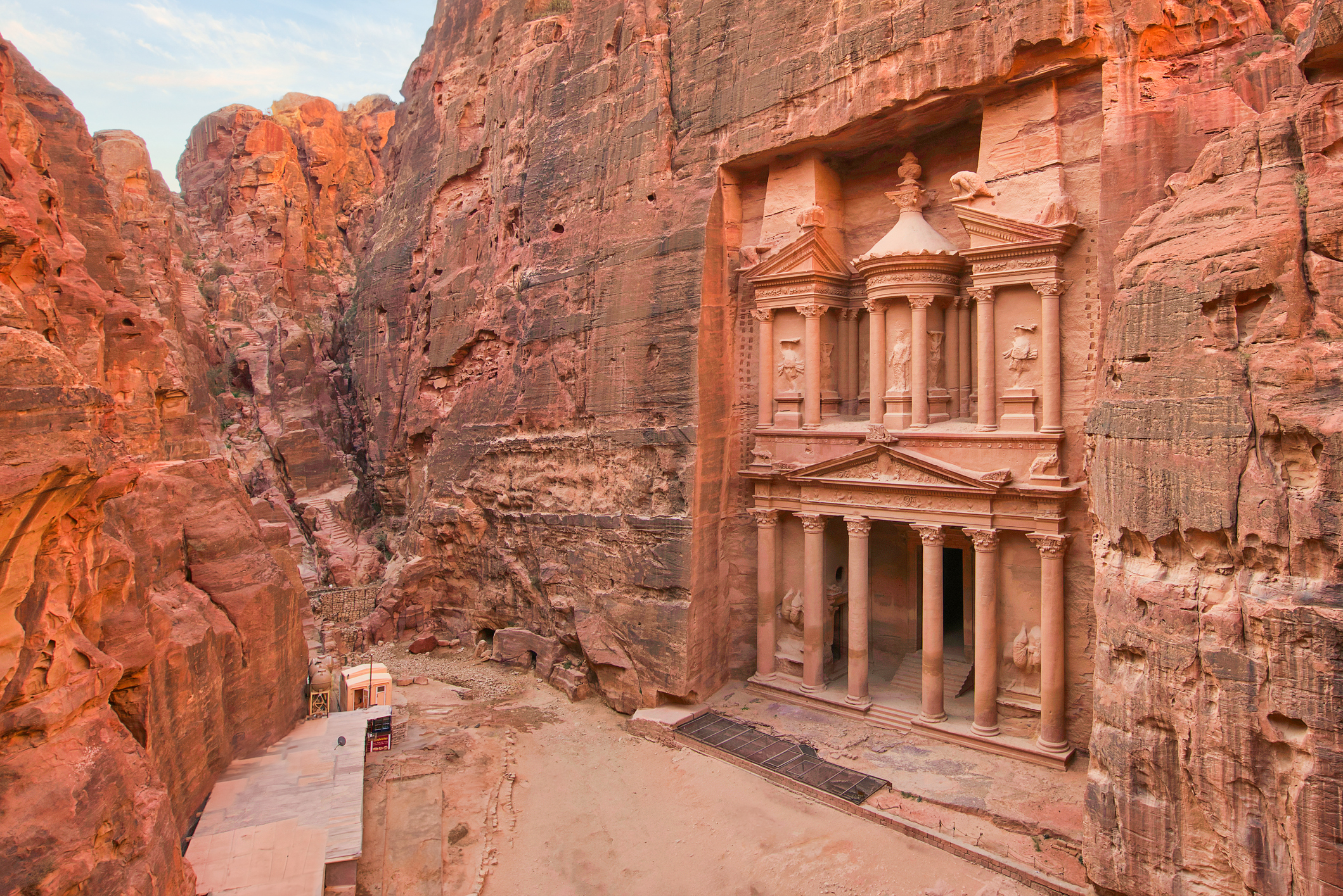 The ancient carved facade of Al-Khazneh in Petra, with rock cliffs surrounding the structure. No people visible