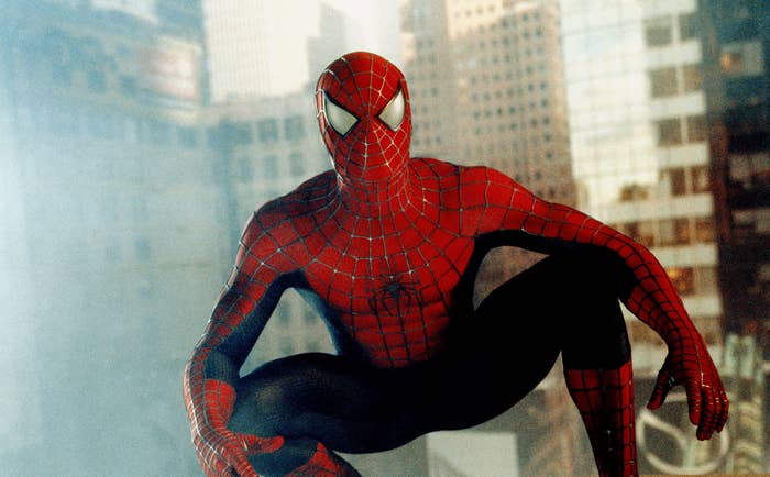 Spider-Man crouched on a building ledge with cityscape in the background