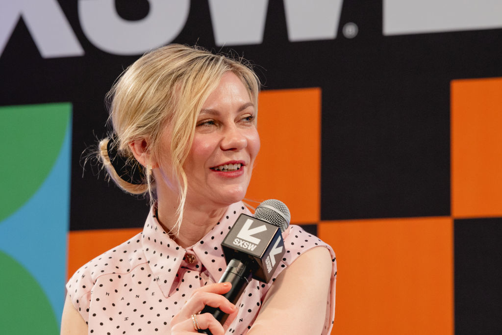 Woman speaking into a microphone at SXSW event, wearing polka dot top