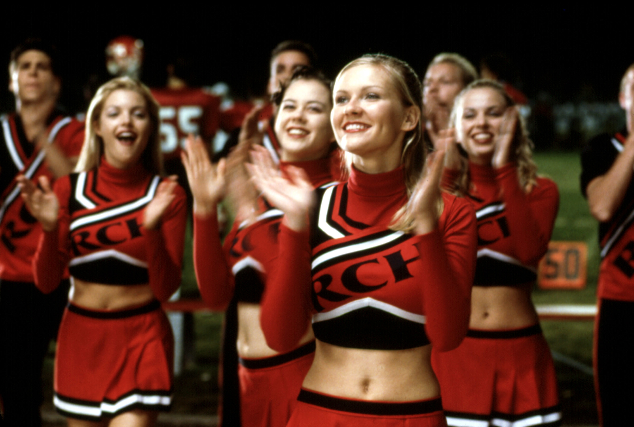 Group of cheerleaders in red and black uniforms performing at a sporting event