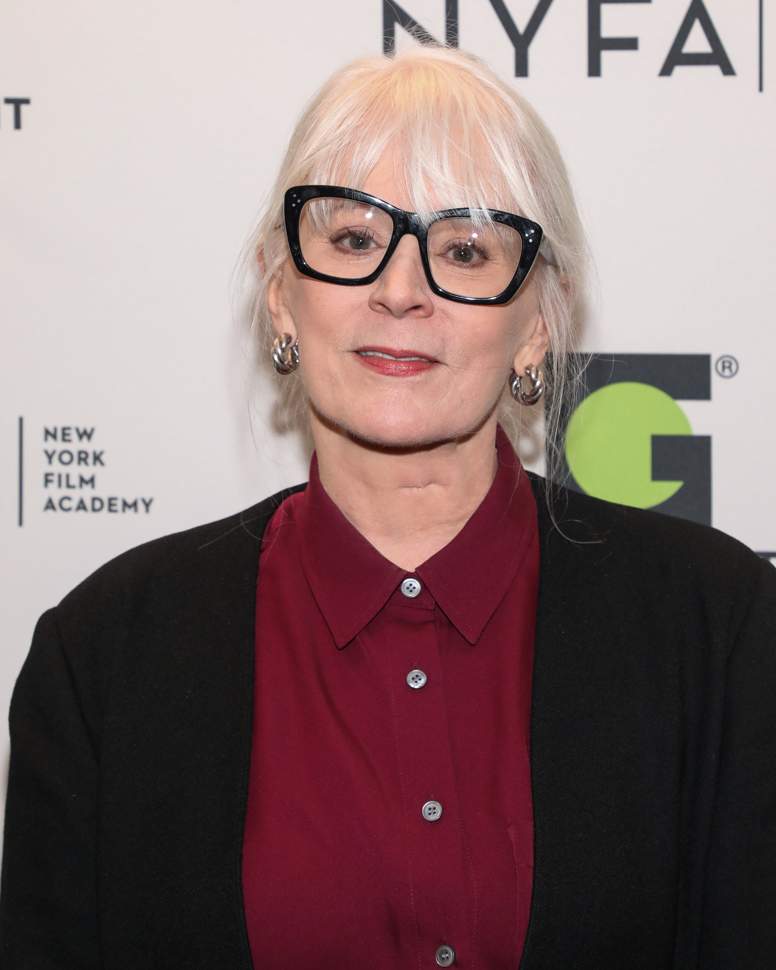Actress in a dark blouse with buttoned collar, glasses, at NYFA event