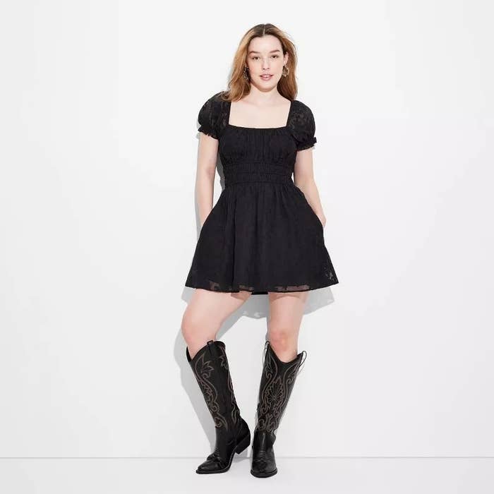Model in black puff sleeve dress