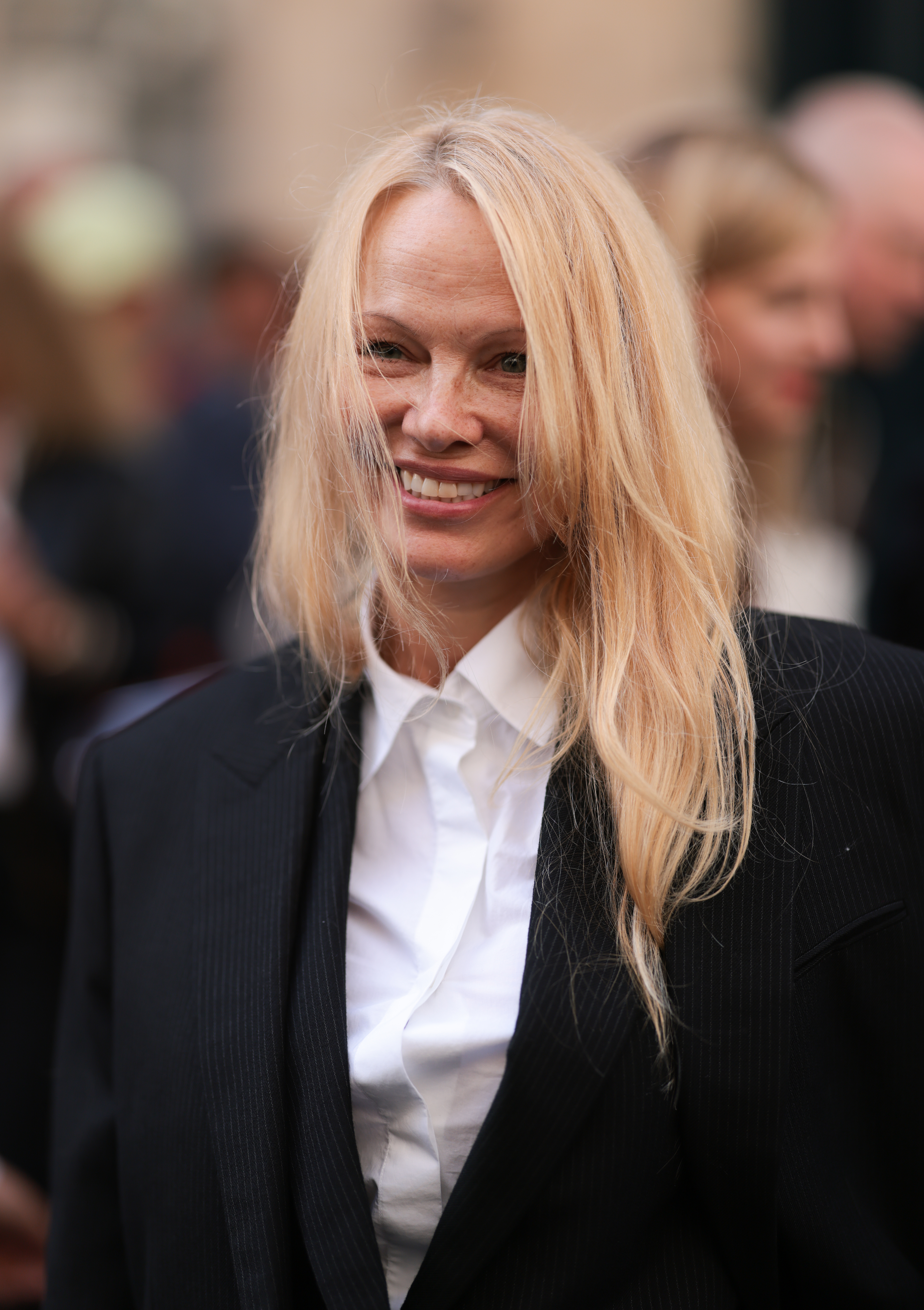 Pamela in a suit smiling on the red carpet with her hair down