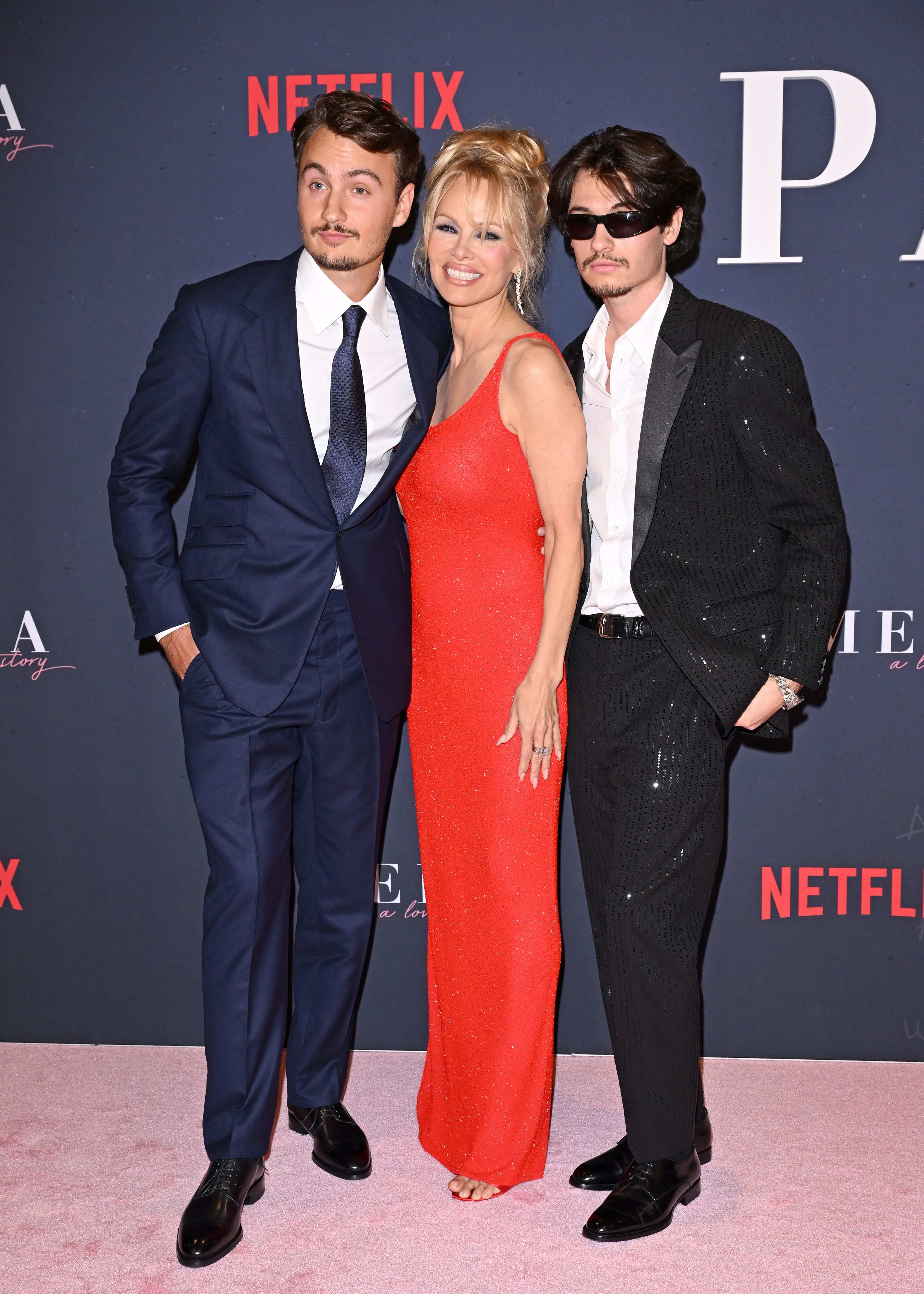 Pamela smiles on the red carpet with her adult sons flanking her
