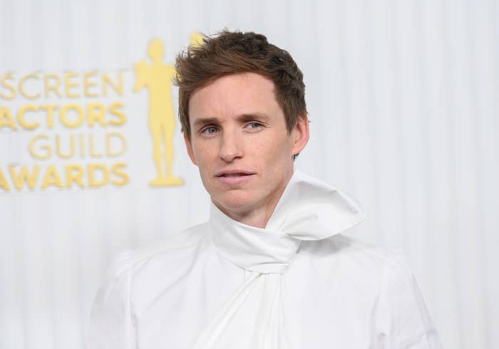 Eddie Redmayne at awards event in a unique tuxedo with large bow at the neck