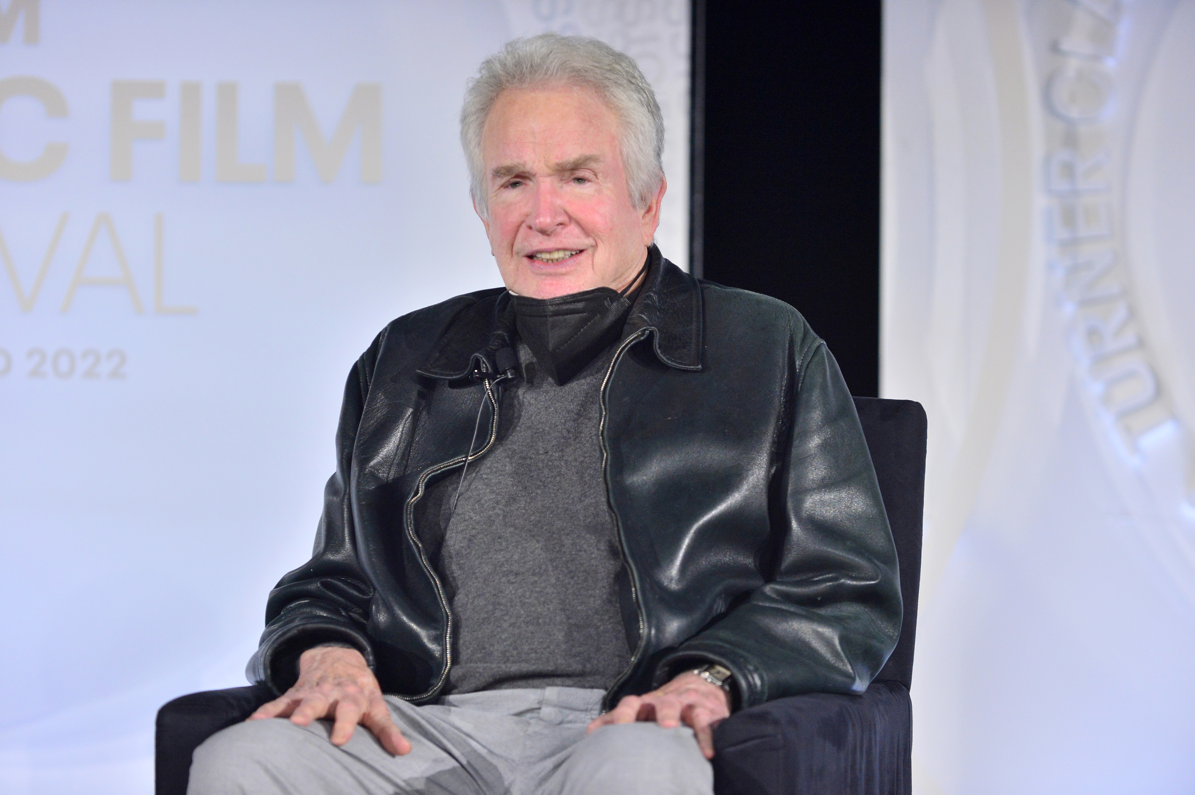 Warren Beatty sits onstage in a leather jacket and turtleneck at the TCM Film Festival 2022