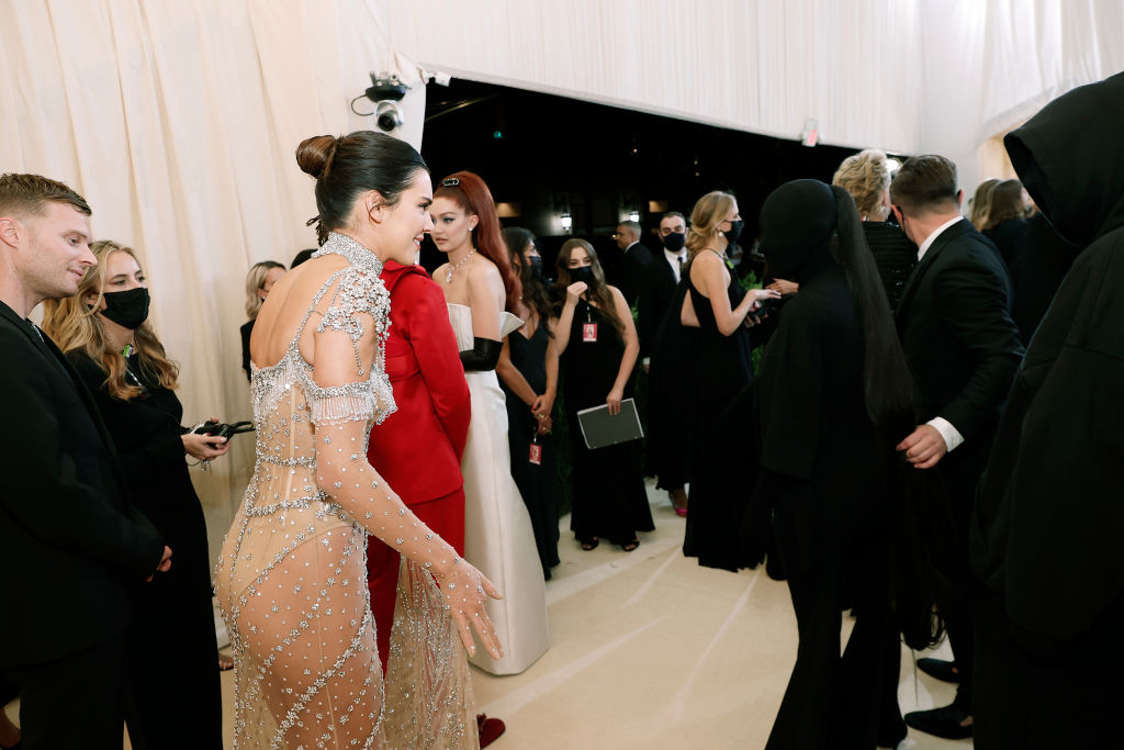 Kendall in a sheer, embellished gown converses with Kim in a full-coverage dark outfit