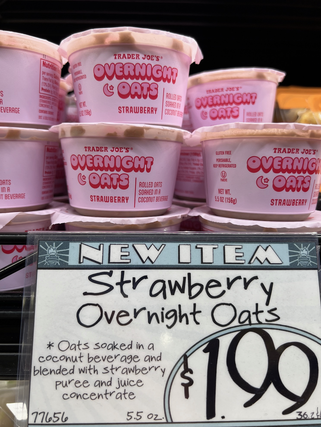 Shelves stocked with containers of Trader Joe&#x27;s new Strawberry Overnight Oats, with a price tag of $1.99 in the foreground