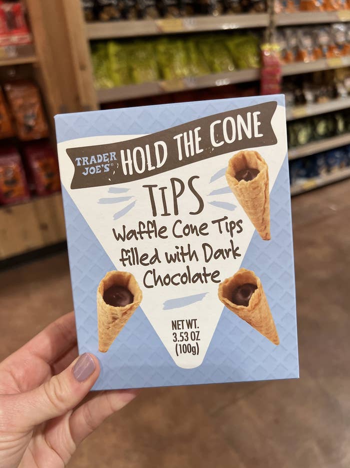 Hand holding a box of Trader Joe&#x27;s Hold the Cone ice cream treats, featuring waffle cones with dark chocolate tips