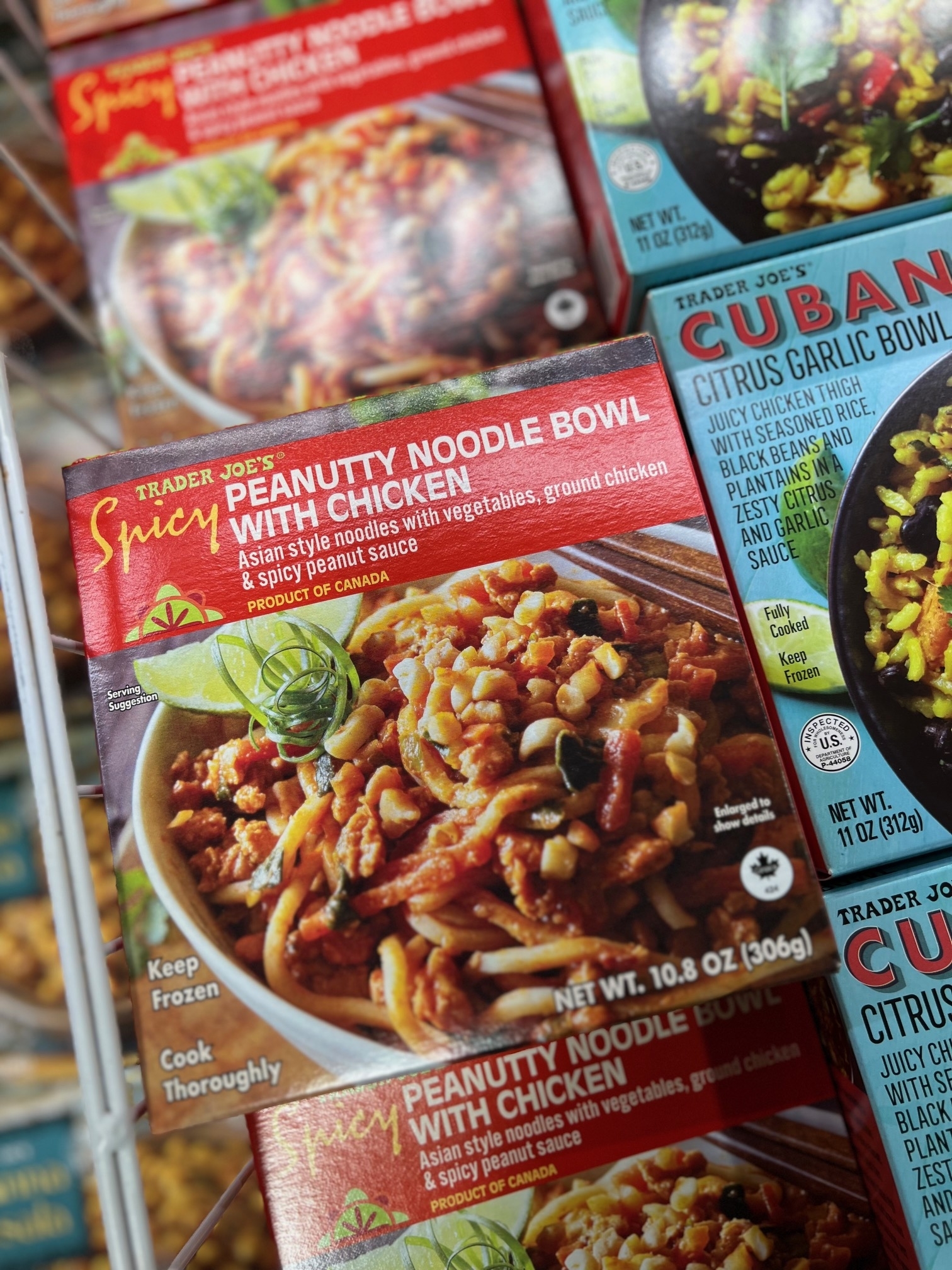Assorted frozen meal boxes on supermarket shelf, with a focus on Spicy Peanutty Noodle With Chicken