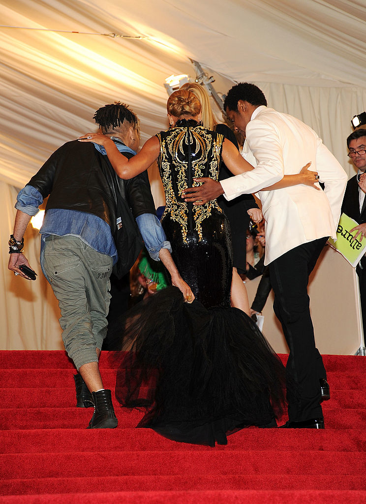 two men escorting Beyoncé in an ornate gown up the stairs at an event