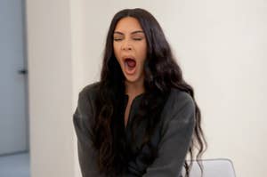 Kim Kardashian is mid-yawn, sitting indoors, suggesting a human moment during a busy schedule likely related to food