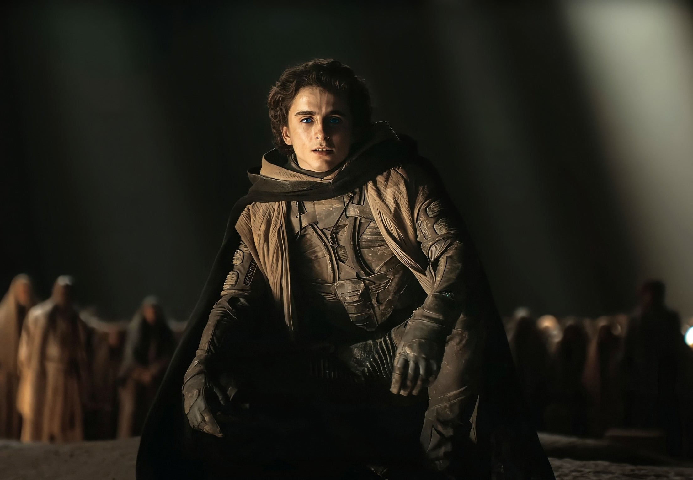 Timothée Chalamet as Paul Atreides in &quot;Dune,&quot; wearing a stillsuit, with a somber expression, in a desert setting at night