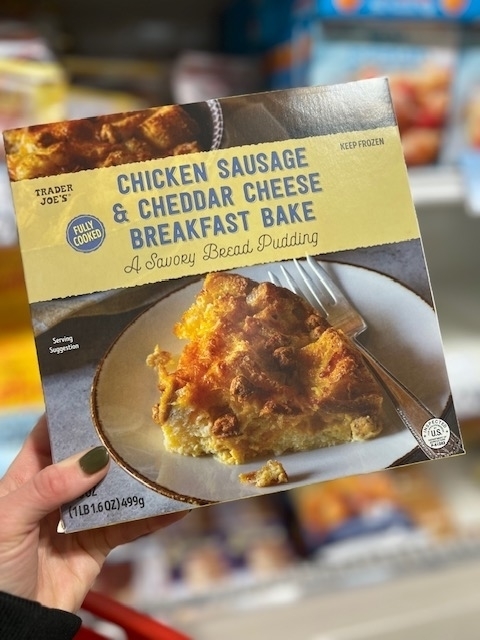 Trader Joe&#x27;s Chicken Sausage &amp;amp; Cheddar Cheese Breakfast Bake packaging held in a hand with grocery shelves in the background