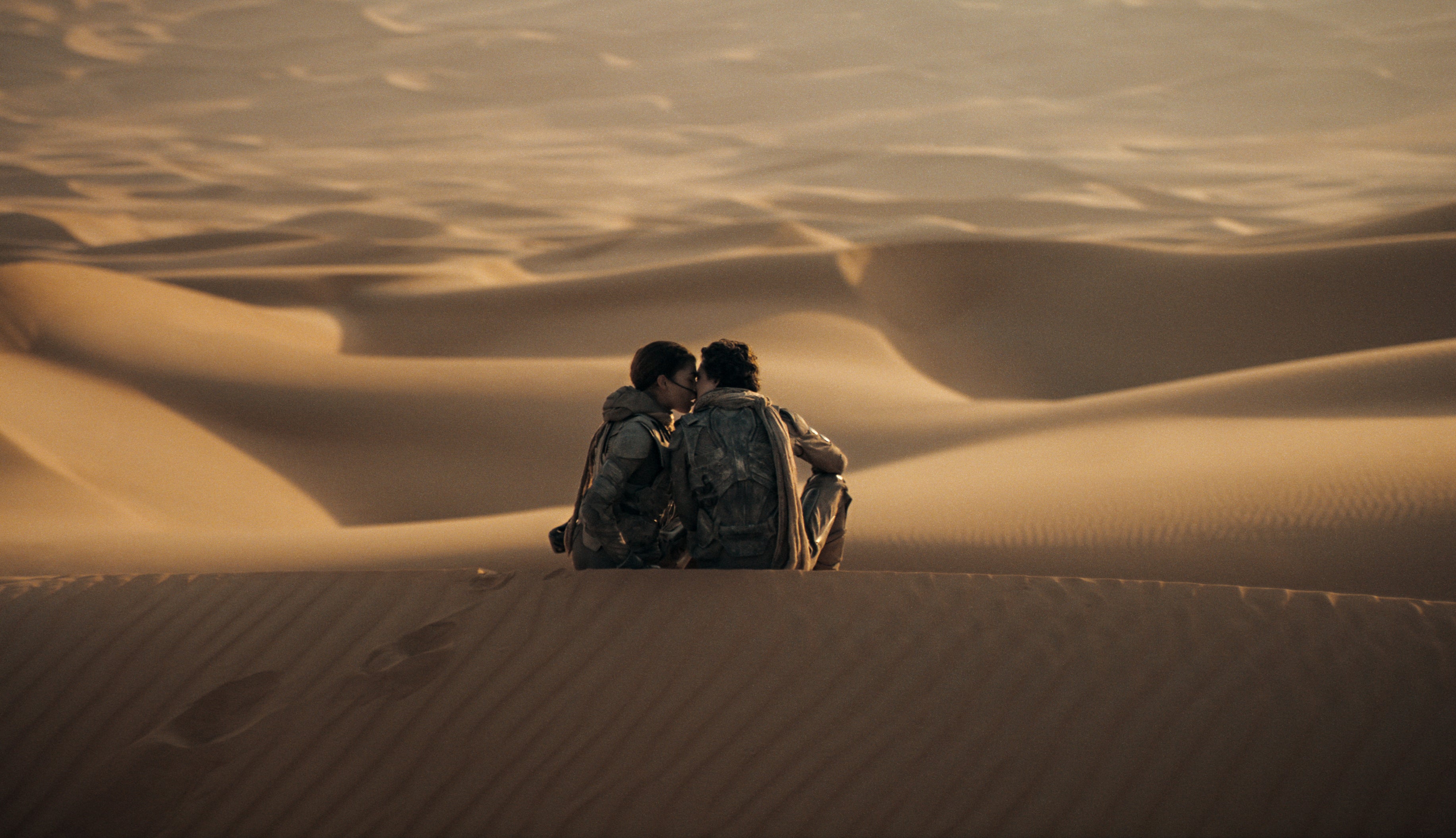 Paul and Chani kissing amidst desert dunes