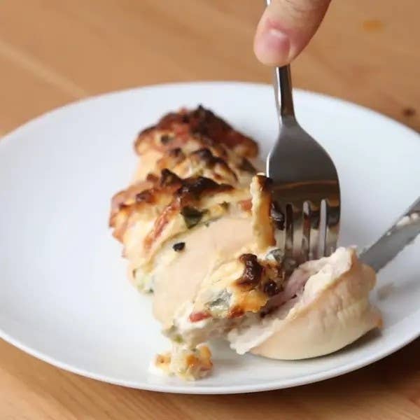 A fork taking a slice of cheesy chicken bake from a plate