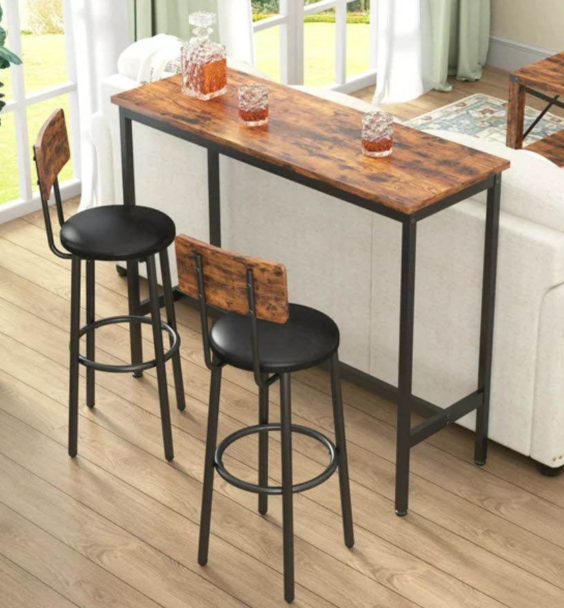 A wooden bar table with two matching stools in a bright room near a window