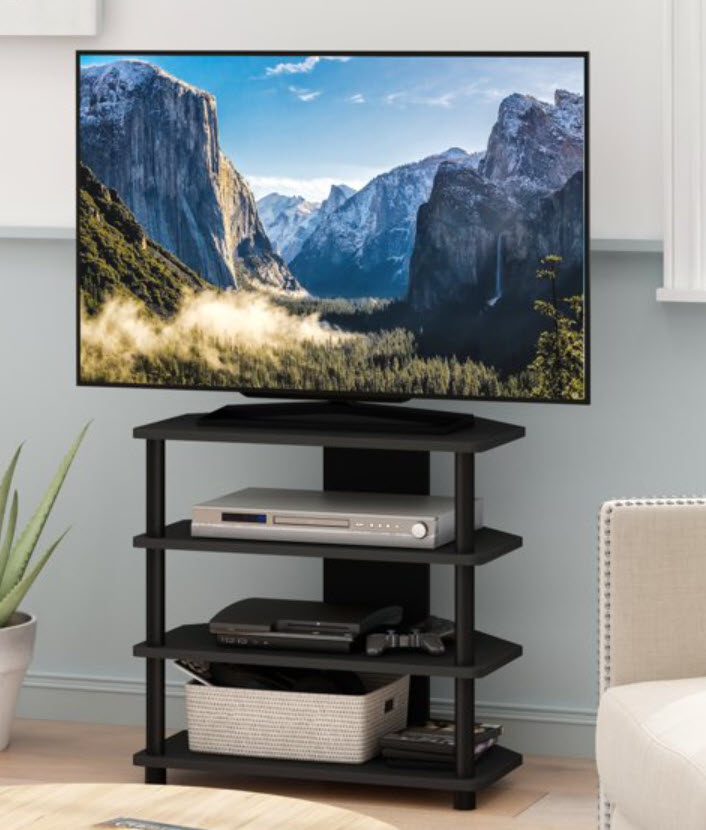 TV on a stand displaying a mountainous landscape with a sofa and plant nearby. No people present