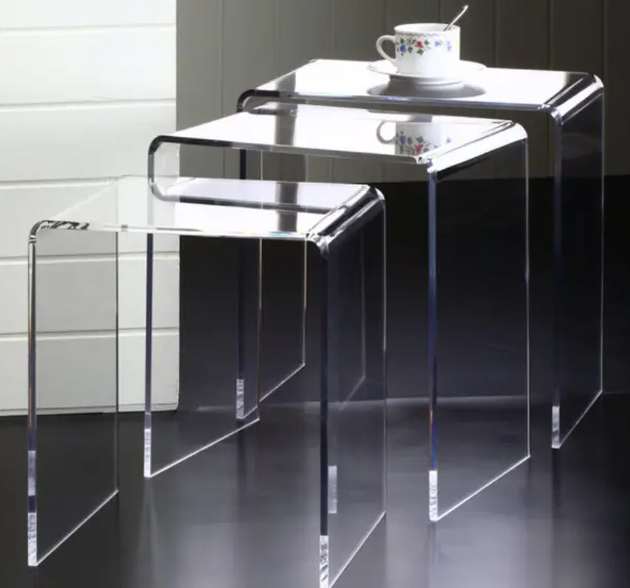 Two transparent acrylic nesting tables with a cup and saucer on the top one
