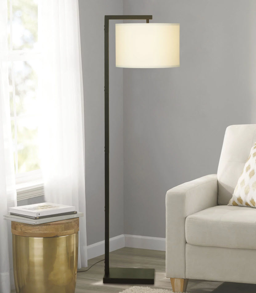 Floor lamp with a white shade next to a beige armchair in a living room setting