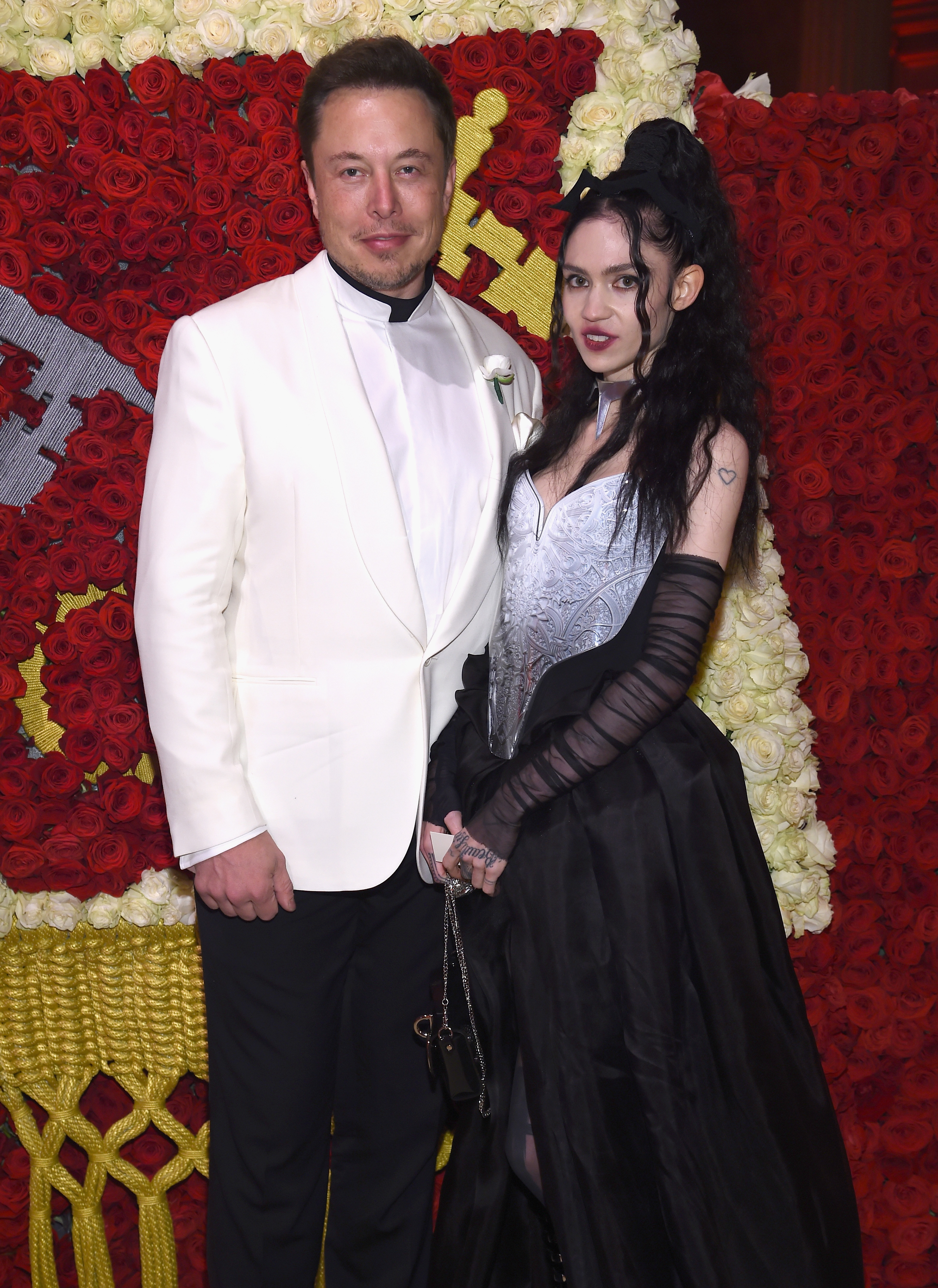 Elon in a white suit and Grimes in a black dress