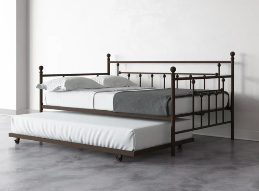 A metal frame bed with a trundle bed underneath, both made up with plain bedding. No people in image