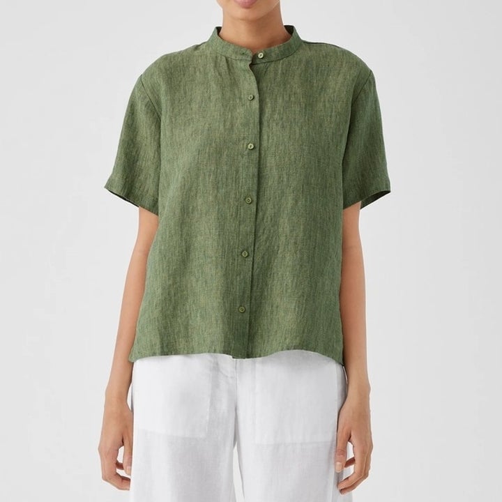 Model in a buttoned, short-sleeve green top paired with white pants