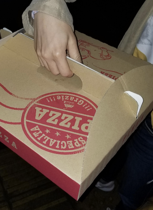 Person holding a pizza box using a handle on top