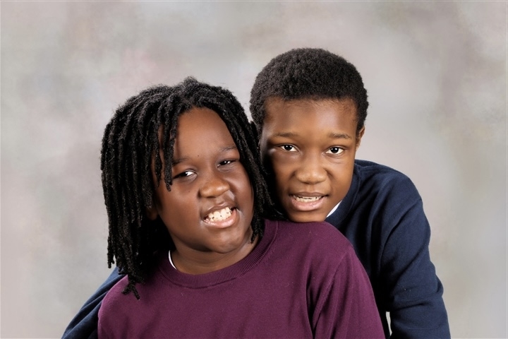 Two smiling children posing closely for a portrait