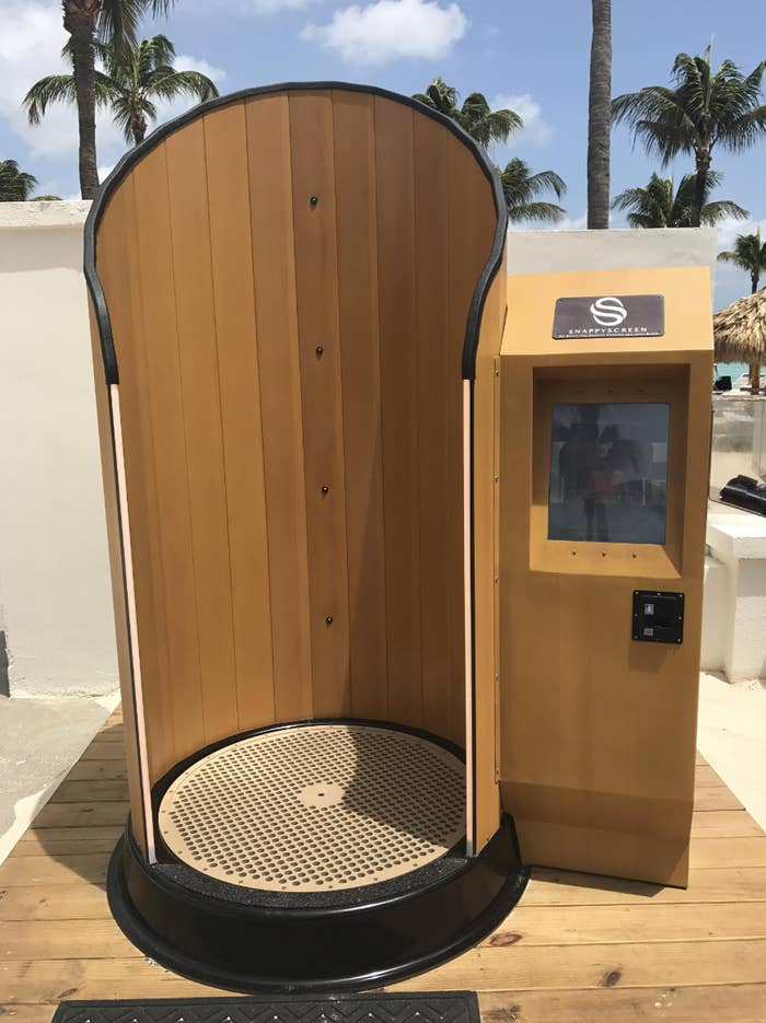 Outdoor wooden machine with a curved top and digital operation panel on a beachfront