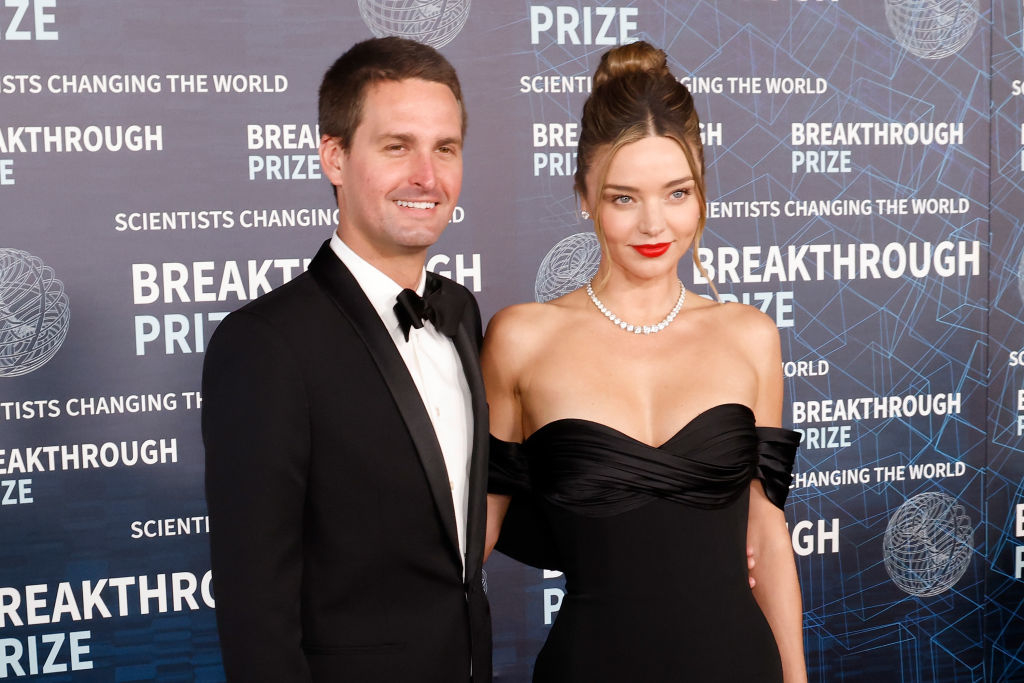 Miranda and Evan pose on the red carpet; one in a black tuxedo, the other in a strapless black gown and pearl necklace