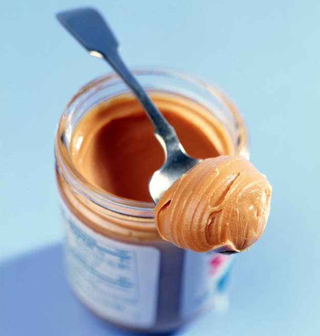 Open peanut butter jar with a spoon sticking out, dollop of peanut butter on the spoon