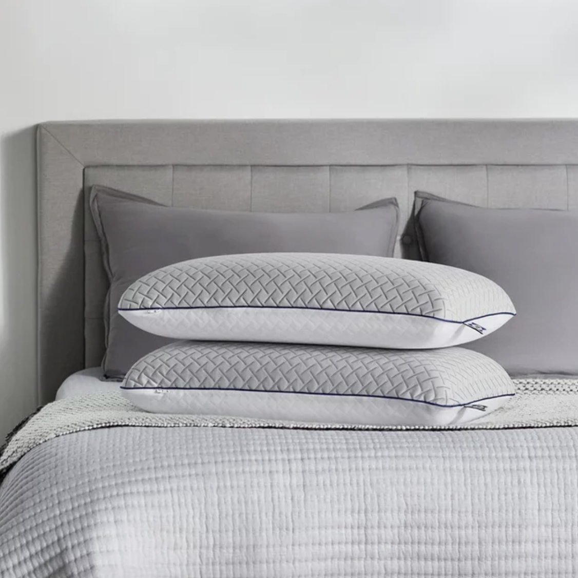Four memory foam pillows on a bed with a textured design