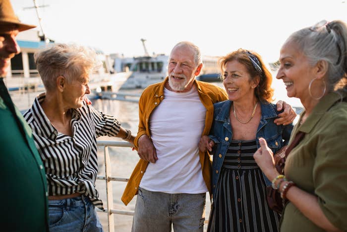 Group of four senior adults enjoying a lively conversation outdoors near boats
