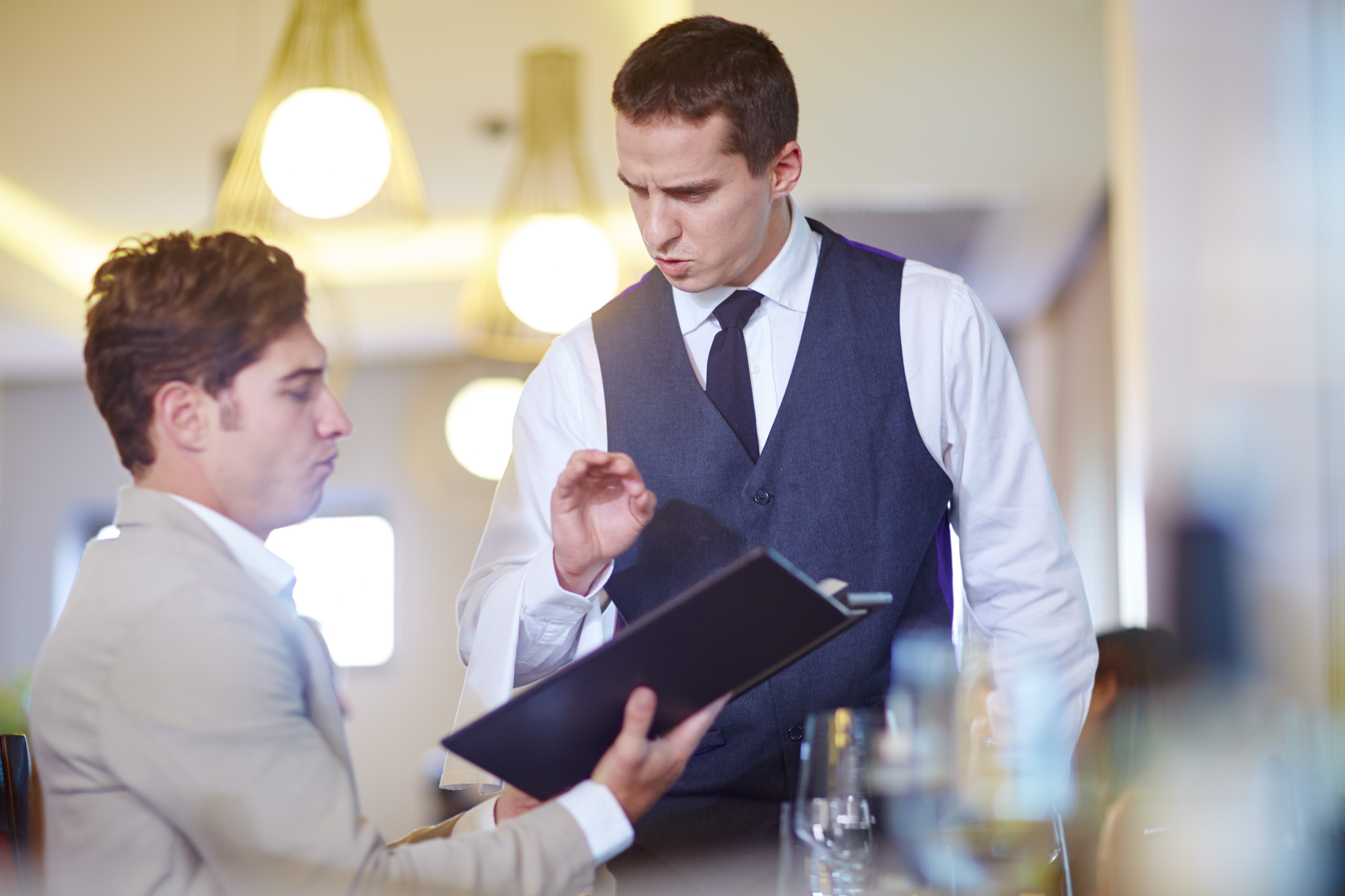 a waiter explaining the menu to a customer