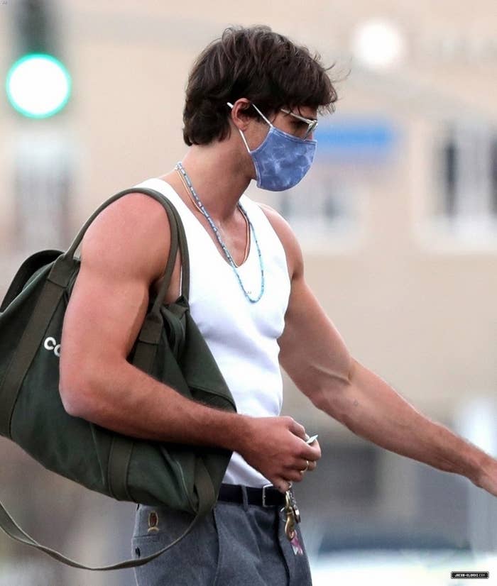 Man in a tank top and mask carrying a backpack and keys