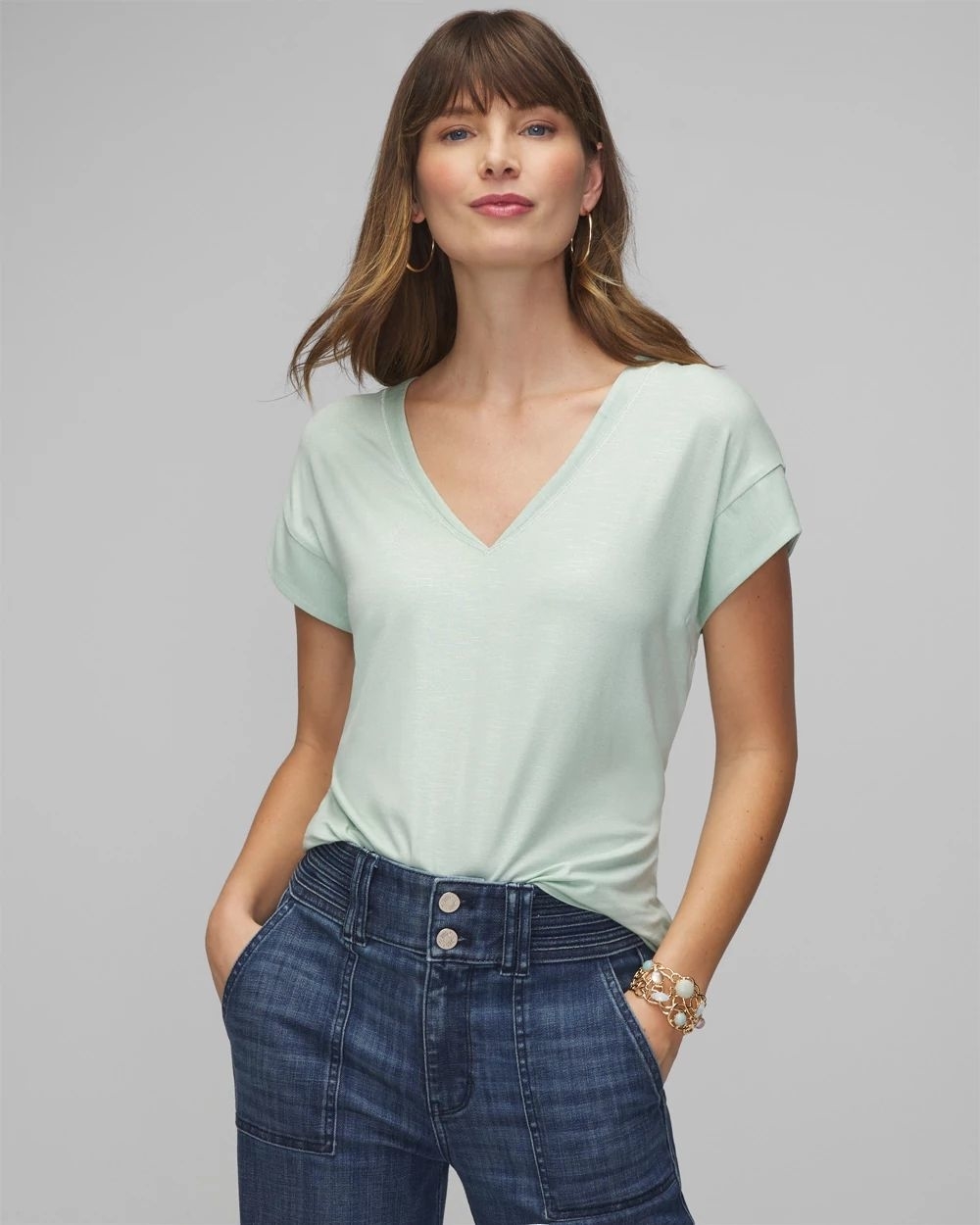 Woman in a V-neck top and high-waisted jeans posing for a shopping article