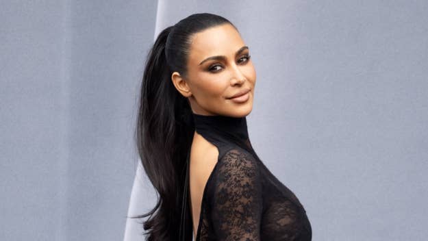 Kim Kardashian posing in a black lace outfit with a high collar