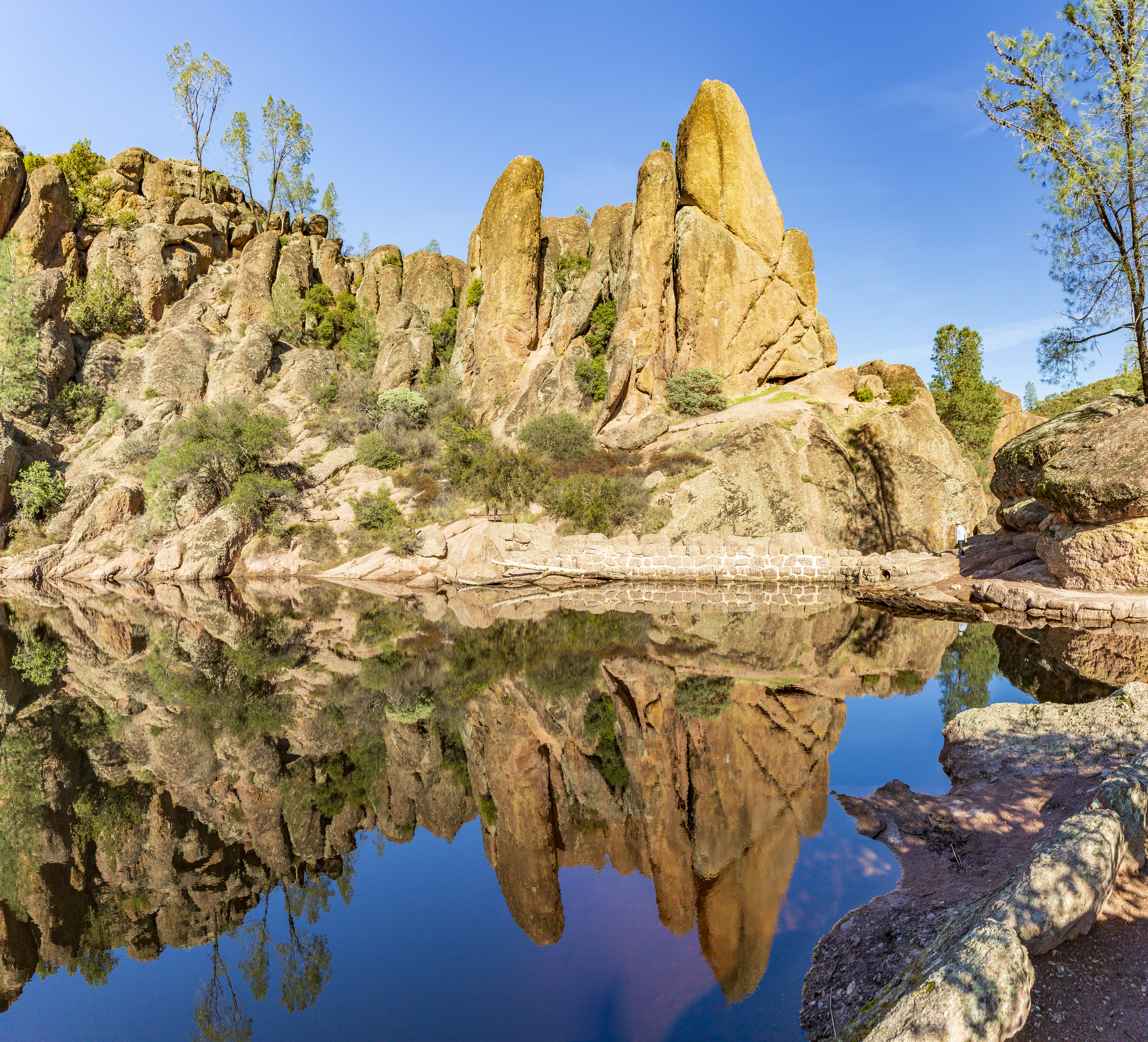 Scenic view of towering rock formations reflected in still water at a tranquil desert oasis