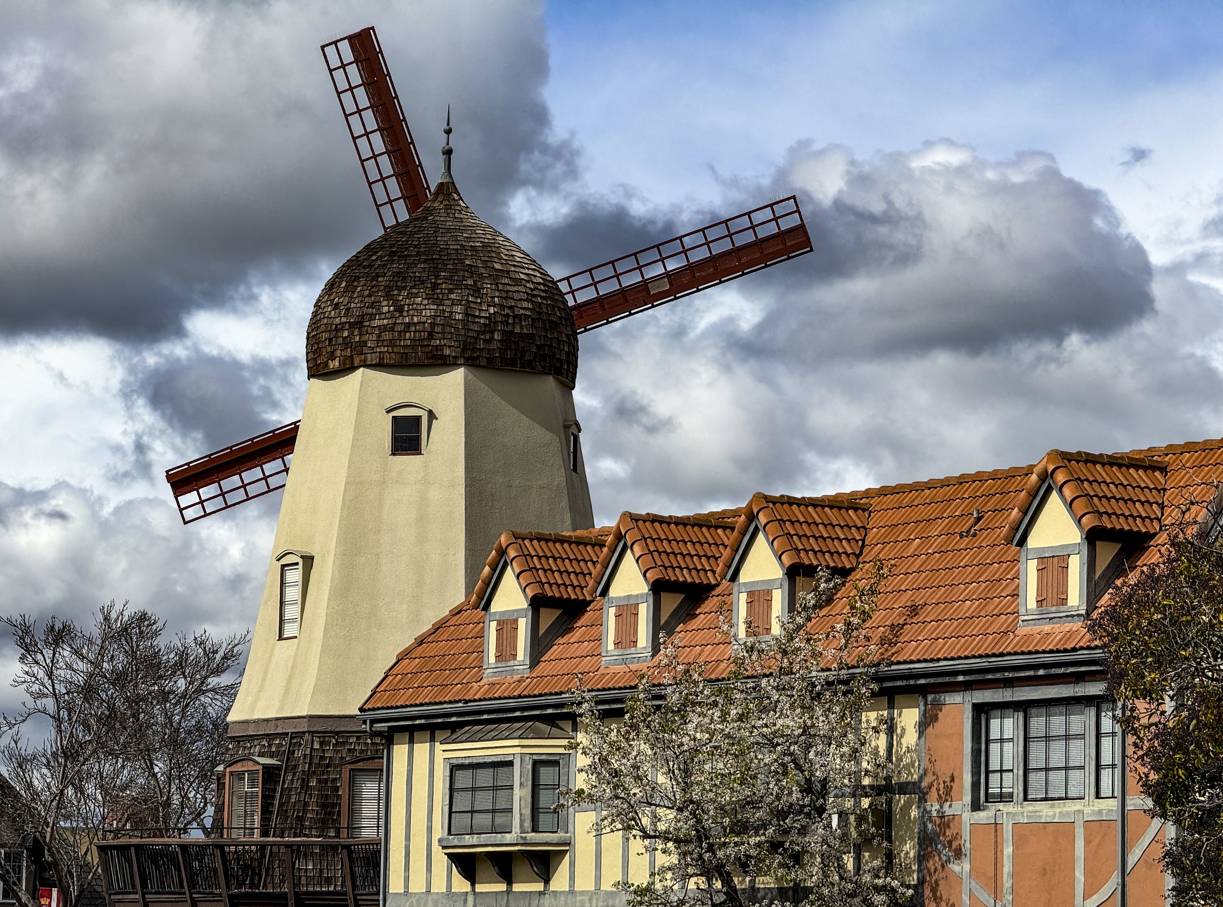 Traditional windmill above European-style building against cloudy sky