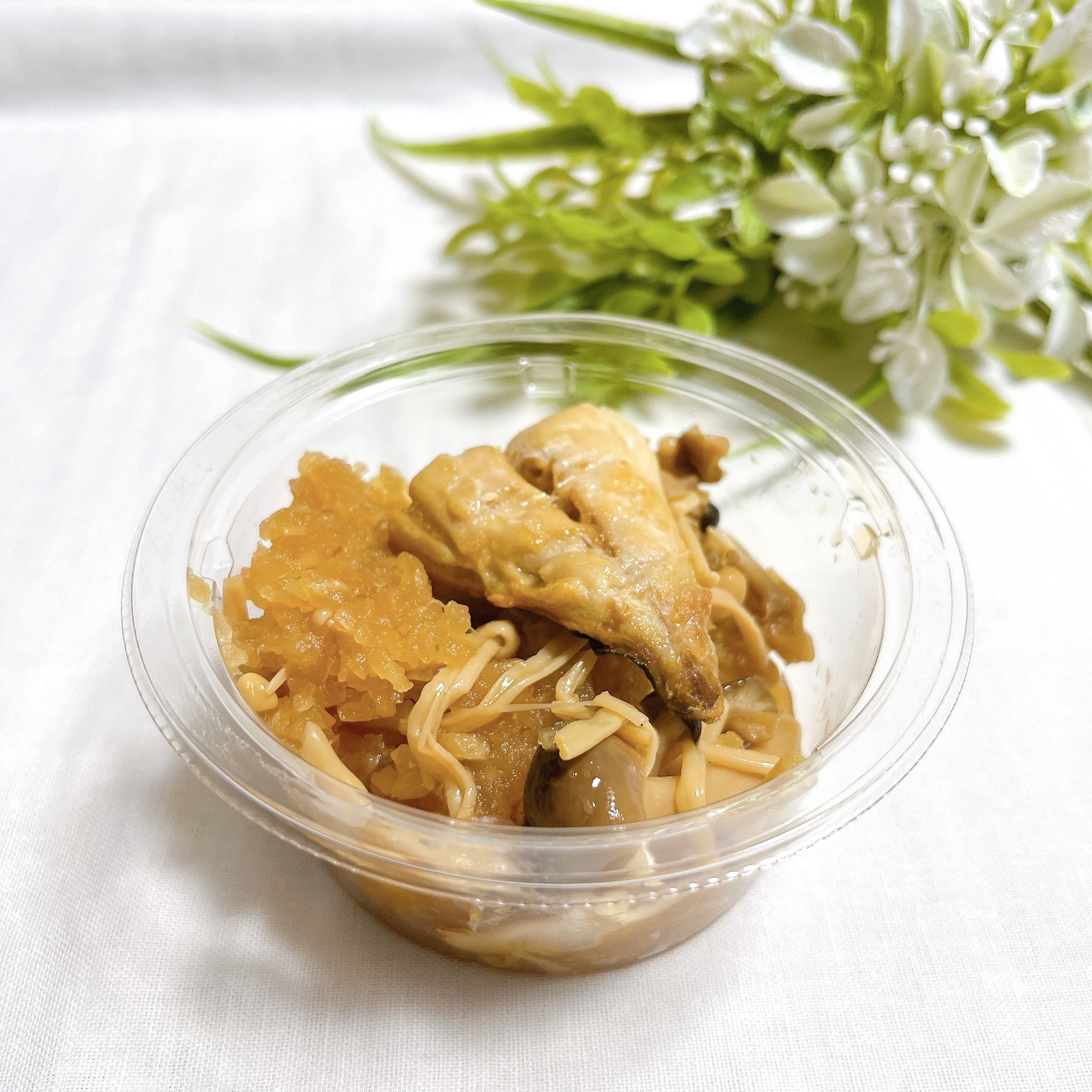 プラスチック容器に入ったチキンと野菜の炒め物。