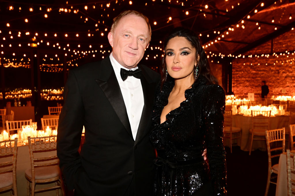 Francois-Henri Pinault and Salma Hayek in formal wear standing together at an event with lights in the background