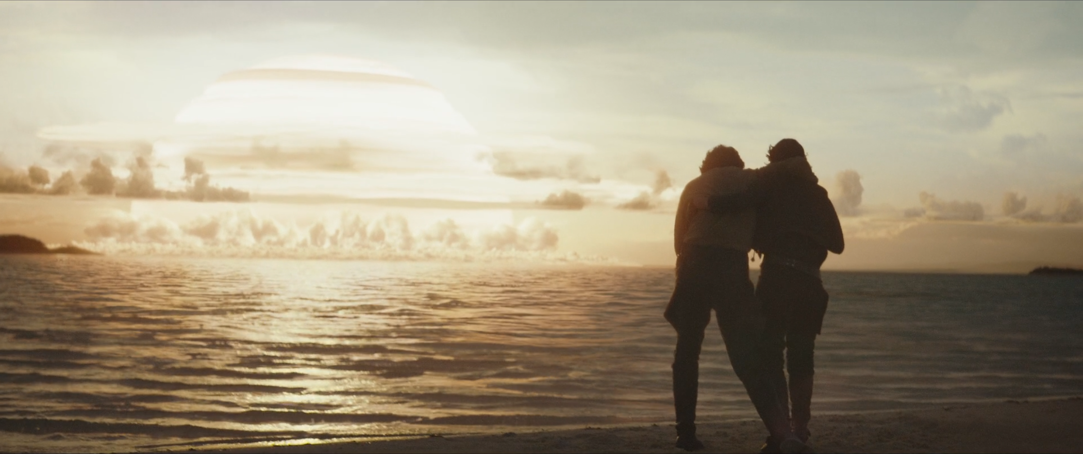 Two silhouetted individuals embracing by the sea at sunset