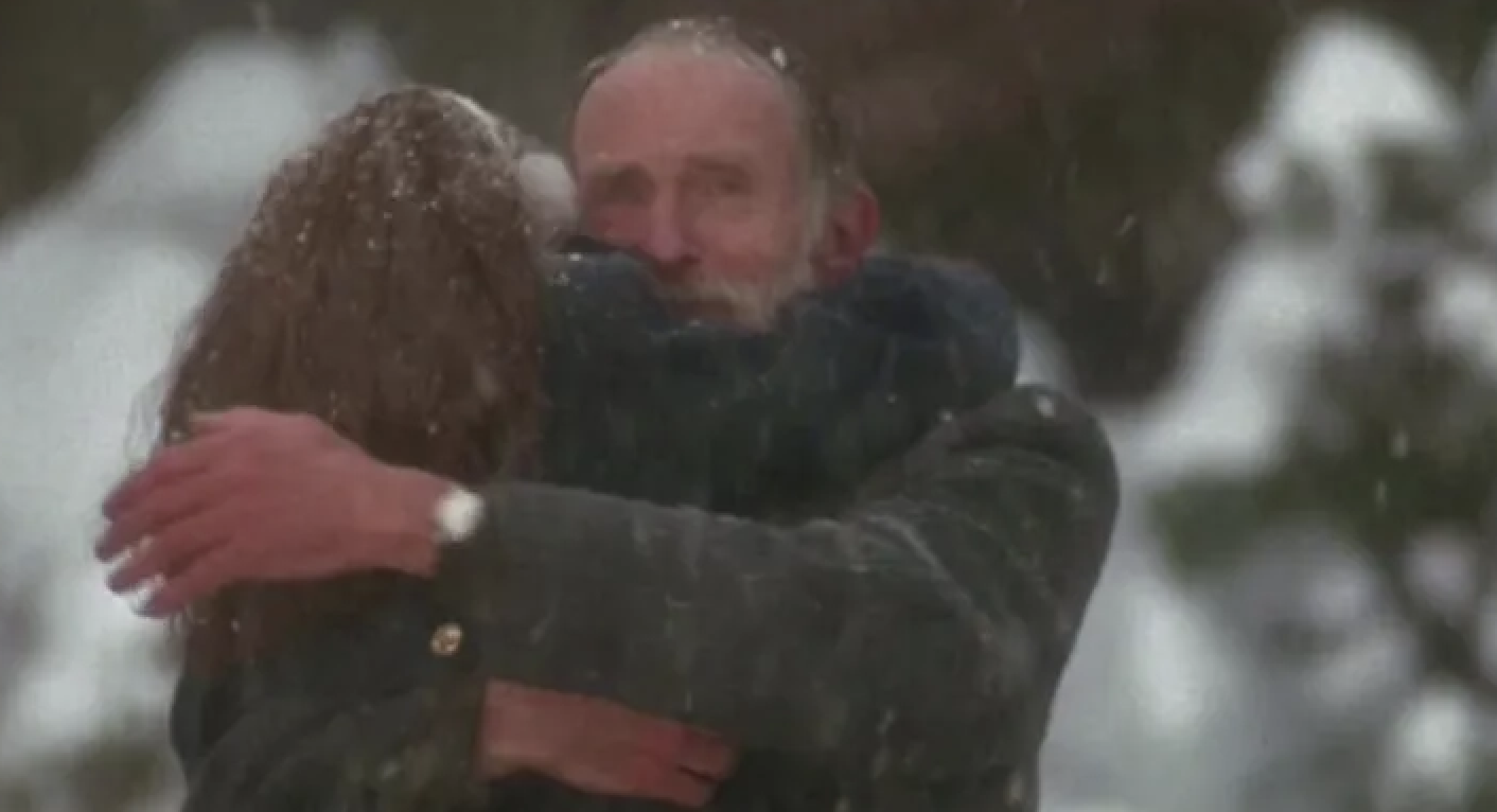 Two characters, a man and woman, embracing in a snowy scene from the film