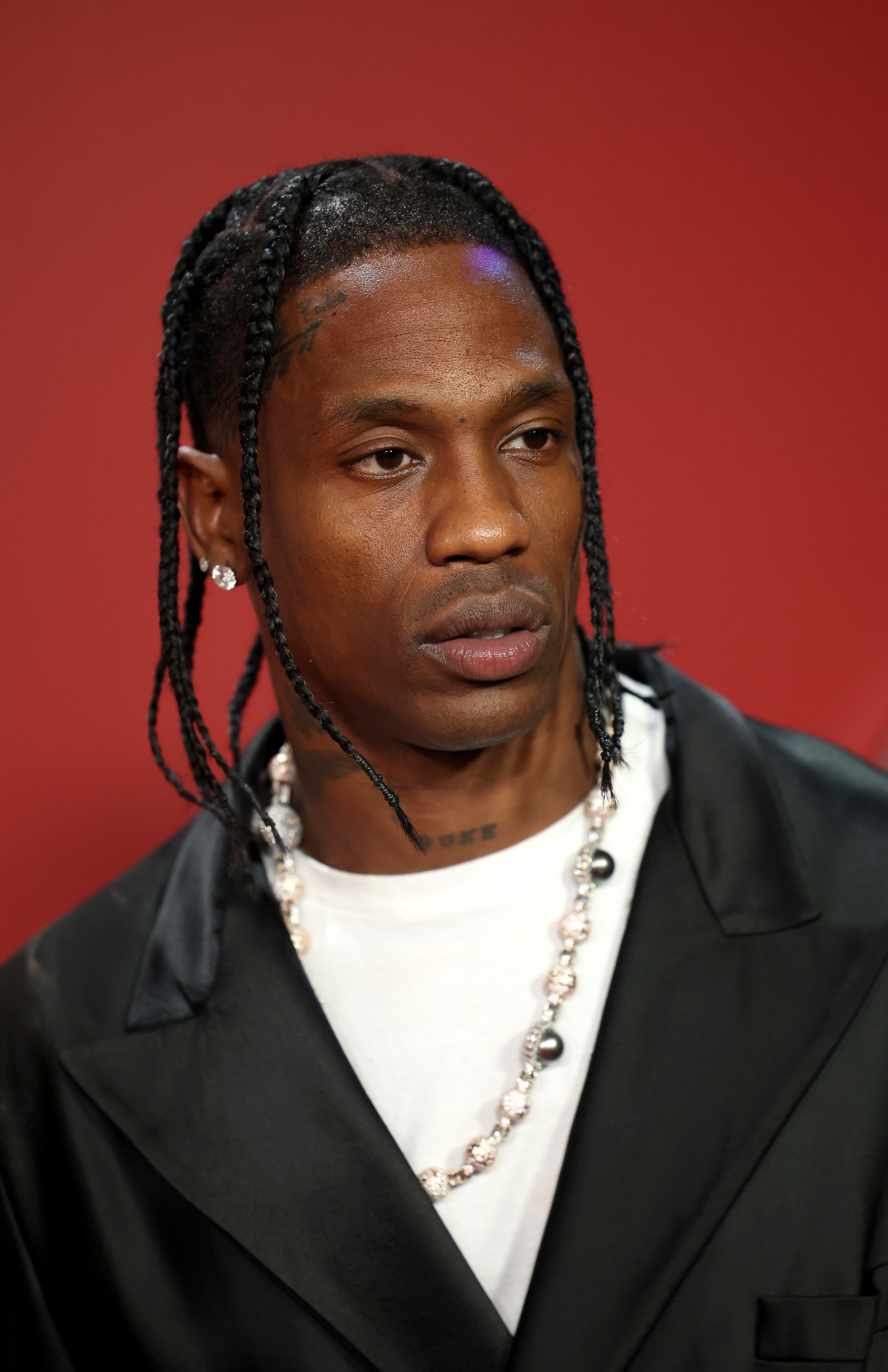 Travis Scott wearing a suit and silver necklace