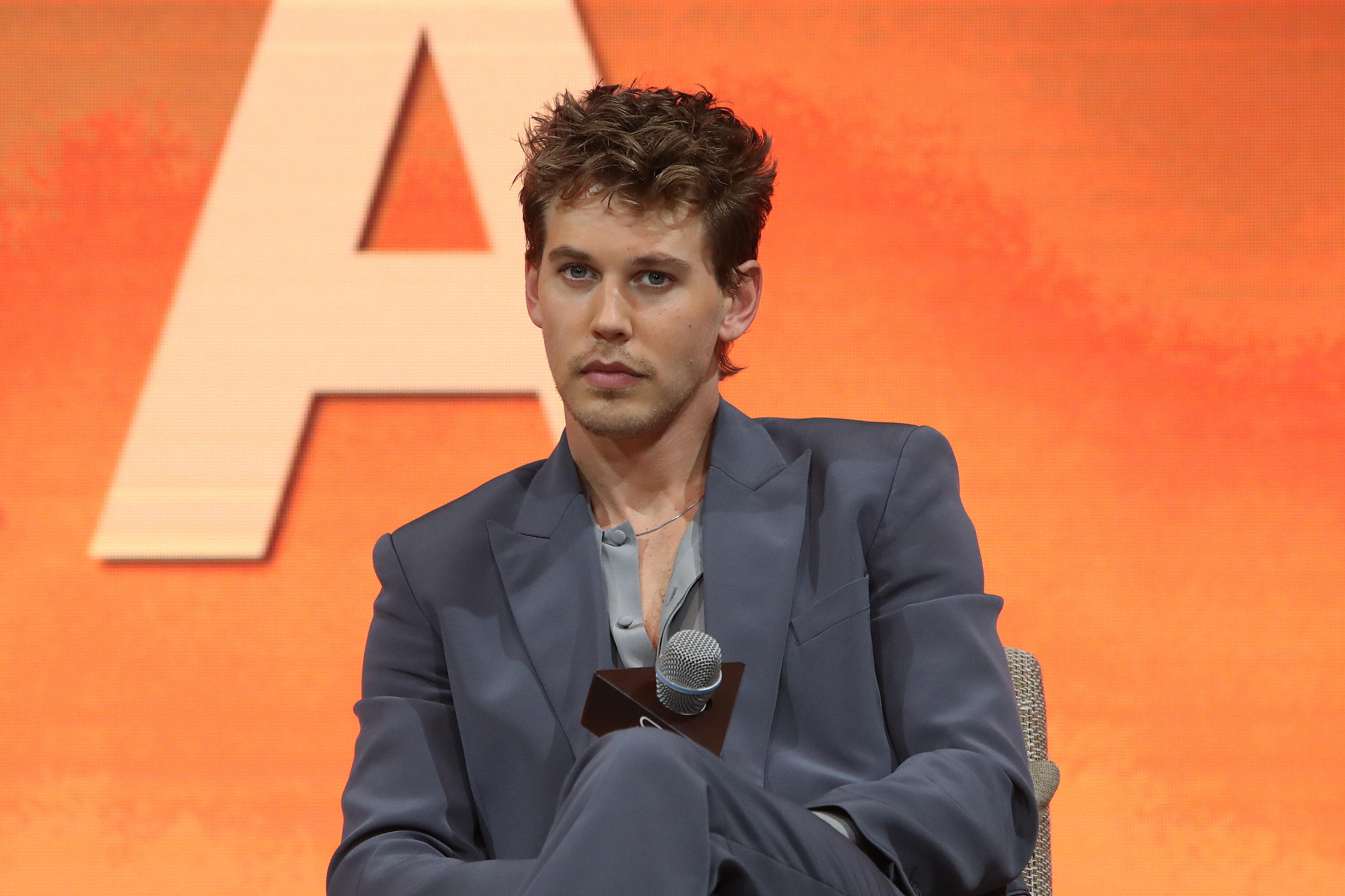 Austin Butler wearing a stylish suit, seated with a microphone in hand